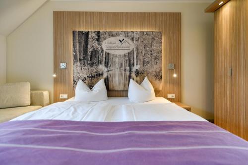 a bedroom with a large white bed with purple sheets at Landhotel Burg im Spreewald - Resort & Spa in Burg