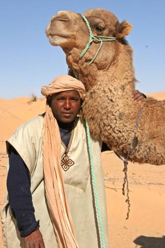 a man standing in the desert with a camel at Maison Proche De Désert Douz in Douz