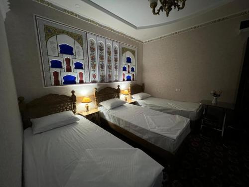 2 Einzelbetten in einem Zimmer mit 2 Lampen in der Unterkunft Zabardast Guest House in Buxoro