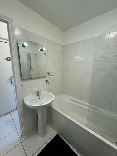 La salle de bains blanche est pourvue d'un lavabo et d'une baignoire. dans l'établissement Le spacieux, au Havre