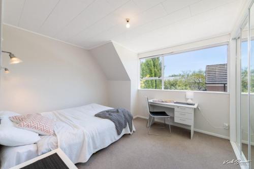 a bedroom with a bed and a desk and a window at 5 bedroom modern house, private spacious backyard in Lower Hutt