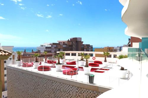 a view of a rooftop patio with red chairs and the ocean at Fantastic apartment in The Wave just steps from Carvajal Beach - Pool and free parking in Fuengirola