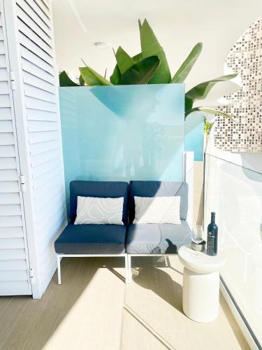 a blue couch in a room with a plant at Fantastic apartment in The Wave just steps from Carvajal Beach - Pool and free parking in Fuengirola