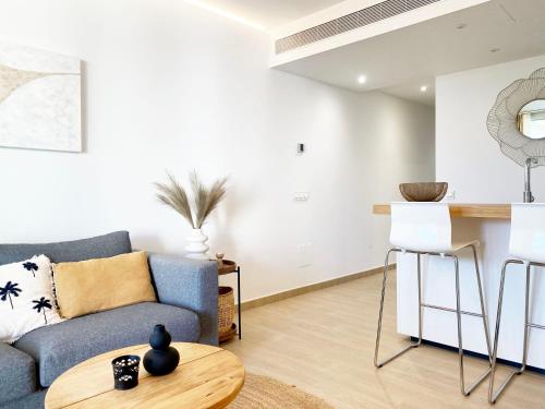 a living room with a blue couch and a table at Fantastic apartment in The Wave just steps from Carvajal Beach - Pool and free parking in Fuengirola