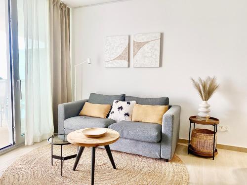 a living room with a blue couch and a table at Fantastic apartment in The Wave just steps from Carvajal Beach - Pool and free parking in Fuengirola