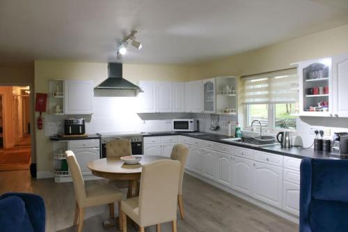 a kitchen with white cabinets and a table and chairs at The Marshes - Large home, short drive to beach in Kells