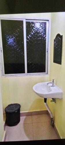 a bathroom with a sink and a window at Hotel Indraprastha (Dey's) in Rāiganj