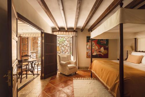 a bedroom with a bed and a chair and a table at La Residencia, A Belmond Hotel, Mallorca in Deia
