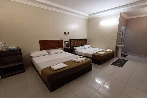 a hotel room with two beds and a bathroom at Fins Hotel, Alor Setar in Alor Setar