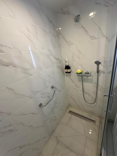een badkamer met een douche en witte marmeren tegels bij ORBI city in Batoemi