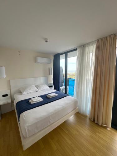 een slaapkamer met een groot bed en een groot raam bij ORBI city in Batoemi