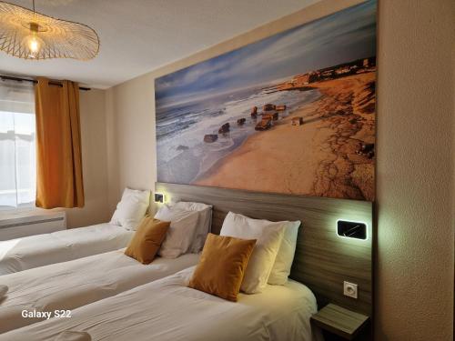 2 camas en una habitación de hotel con un cuadro en la pared en Hotel Eisenhower (ex King Hôtel) en Port-en-Bessin-Huppain