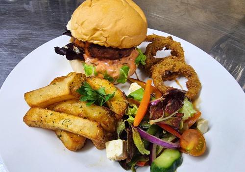 a white plate with a sandwich and a salad and fries at Imbabali Retreat & Venue in Magaliesburg