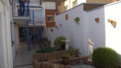 a courtyard of a white building with plants and a staircase at Kokodor in De Haan