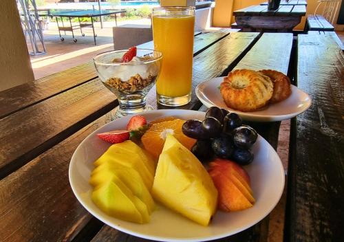 two plates of fruit on a wooden table with drinks at Imbabali Retreat & Venue in Magaliesburg