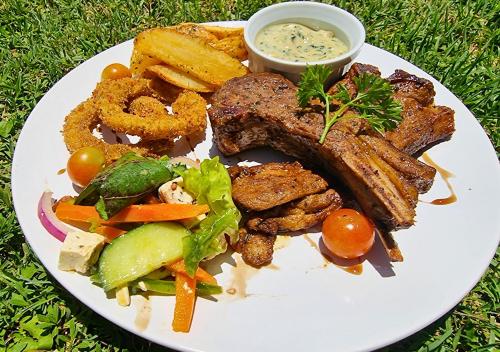a plate of food with meat and vegetables and dipping sauce at Imbabali Retreat & Venue in Magaliesburg