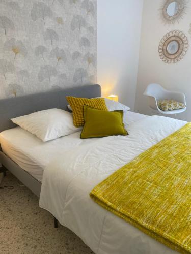 Un dormitorio con una cama blanca con almohadas amarillas. en Profitez De La Vue !, en Banyuls-sur-Mer