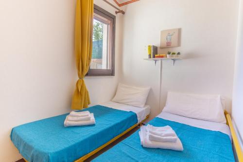 two twin beds in a room with a window at [COSTA REI] *500 metri dal mare* Free Parking/Wifi in Costa Rei