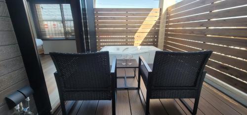 two chairs and a table on a balcony with a hot tub at ROMANSTAY in Takayama