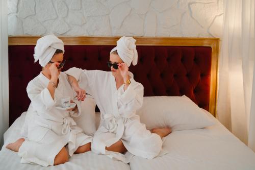 twee vrouwen in witte handdoeken zittend op een bed bij Hotel Podklasztorze in Sulejów