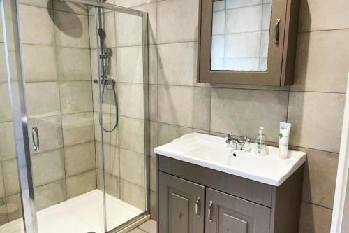 ein Bad mit einem Waschbecken und einer Dusche mit einem Spiegel in der Unterkunft Aghadoe Millers - Modern 3 bed house Killarney in Fossa