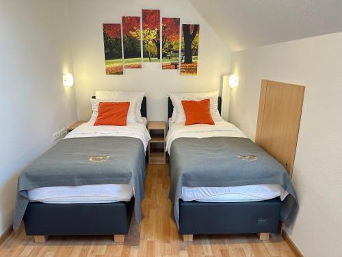 two beds in a small room with paintings on the wall at Boutique Hotel Loka in Škofja Loka