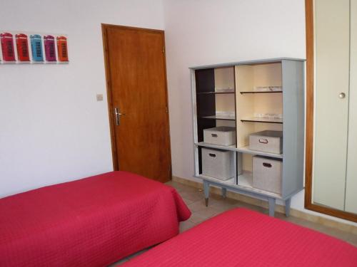 Cette chambre comprend un lit rouge et une armoire avec des boîtes. dans l'établissement LE GITE D'HENRI 1- Maison individuelle -3 chambres, à Chorges