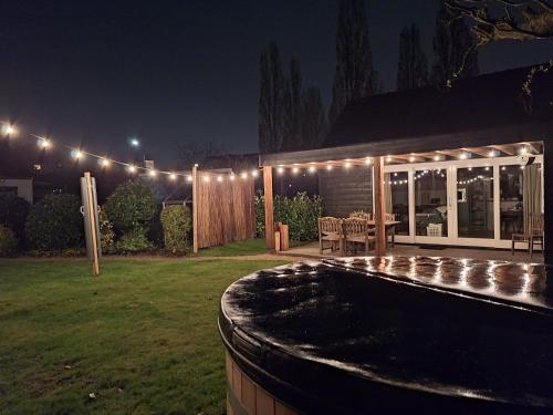 un patio trasero con piscina por la noche con luces en In de bocht - Hottub Sauna, en Gemonde