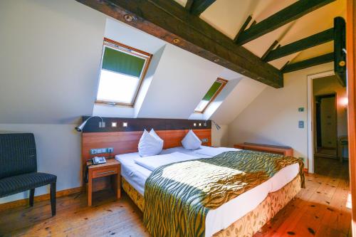 a bedroom with a bed and a chair in it at Landhotel Burg im Spreewald - Resort & Spa in Burg