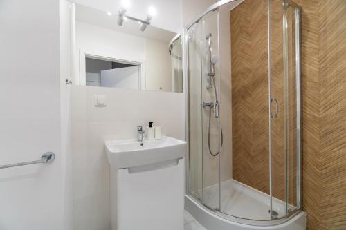 a white bathroom with a shower and a sink at Silver Forest in Szczecin
