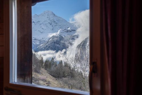 a view of a mountain through a window at Chalet Schweizerhof Attic in Wengen