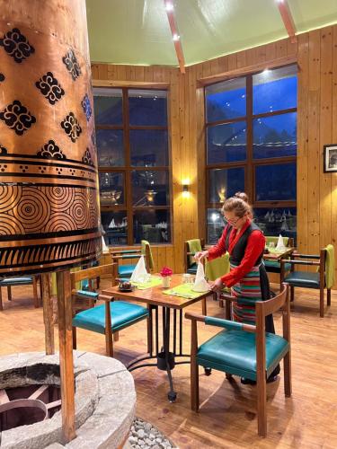 Eine Frau, die an einem Tisch in einem Restaurant steht. in der Unterkunft Mountain Lodges of Nepal - Phakding in Phakding