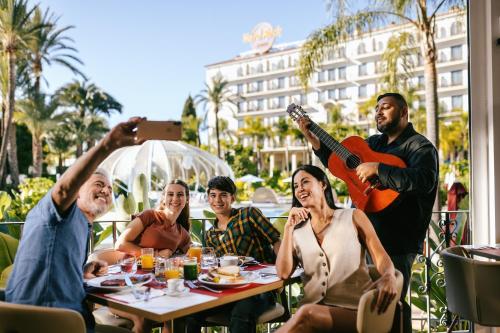 a group of people sitting around a table with a guitar at Hard Rock Hotel Marbella - Puerto Banús in Marbella