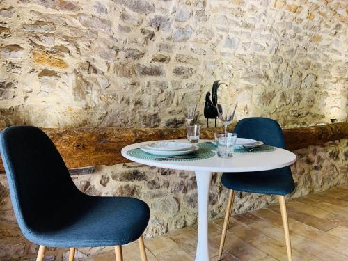 une table blanche avec deux chaises et une table avec des verres dans l'établissement Relais de Poste apartment South Ardèche, à Saint-André-de-Cruzières