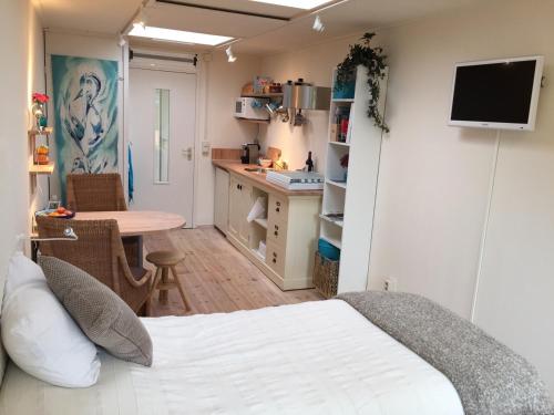 a bedroom with a bed and a kitchen with a table at BBBoekelo appartement in Boekelo