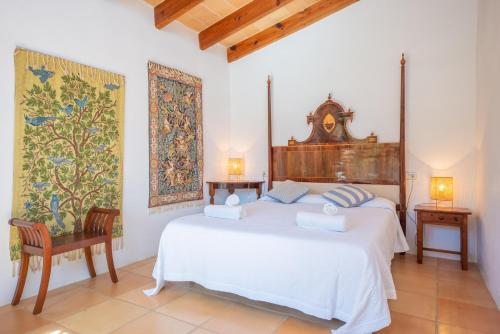a bedroom with a white bed and a clock on the wall at Son Poca Palla in Sant Llorenç des Cardassar