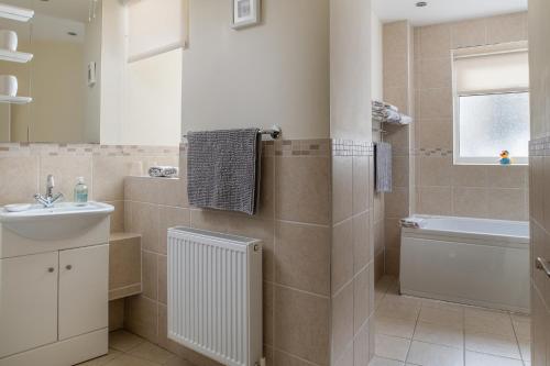 uma casa de banho com um lavatório, uma banheira e um WC. em Puffin View em Llanfairfechan