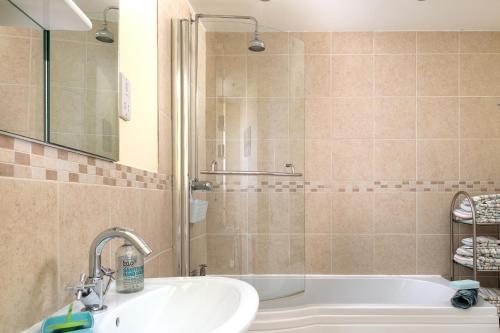 a bathroom with a shower and a sink and a tub at Orme View in Llanfairfechan