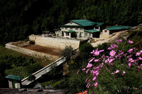 Mountain Lodges of Nepal - Monjo في Monjo: منزل على قمة تل به زهور