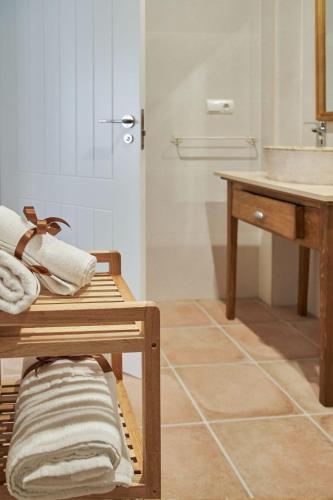 a bathroom with a sink and a shelf with towels at Casas Rurales El Aljibe, Jara in Argés