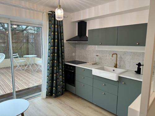 Il dispose d'une cuisine avec un évier et d'une fenêtre avec une terrasse. dans l'établissement L'Écrin de Marie-Lou Studio Cosy, à Chaponost