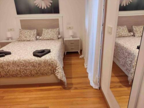 een kleine slaapkamer met 2 bedden en een spiegel bij Apartamento Playa de Coroso in Ribeira