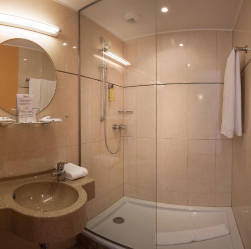 y baño con ducha, lavabo y bañera. en Hotel Parc Plaza, en Luxemburgo