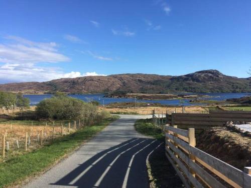 a road with a fence next to a body of water at Heaste Retreat in Broadford