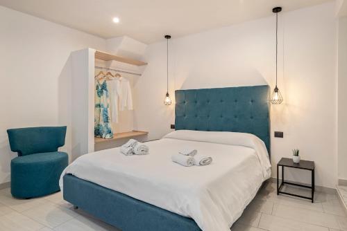 a bedroom with a large bed and a blue chair at B&B Casa Giunchiglia in Noto