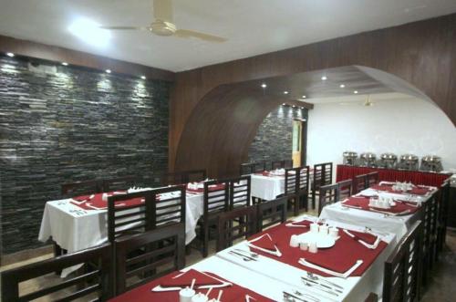 a dining room with tables and chairs and a brick wall at Hotel Green Leaf , Srinagar in Srinagar