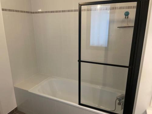 La salle de bains est pourvue d'une baignoire avec une porte de douche en verre. dans l'établissement Family Appartment with balcony, à Saint-Cyr-lʼÉcole