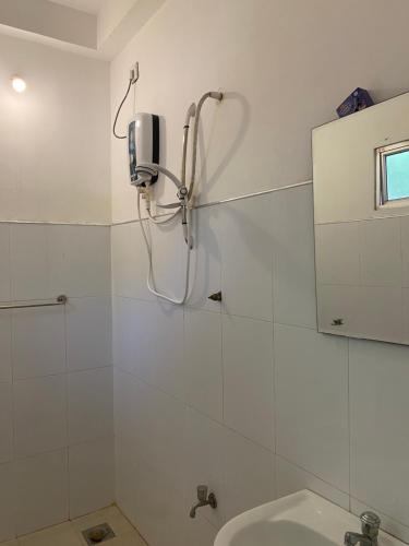 a white bathroom with a shower and a sink at Talalla Ocean Beach Bungalow in Matara