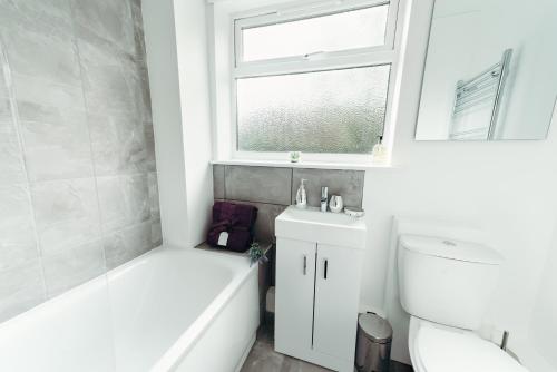 ein Badezimmer mit einer Badewanne, einem WC und einem Waschbecken in der Unterkunft Sophisticated 2BR retreat for Contractors in charming Hinckley in Hinckley