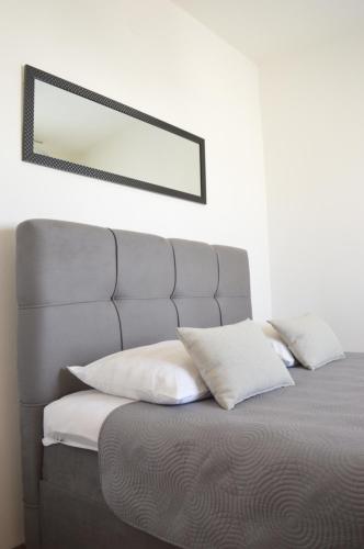 a bed with white pillows and a mirror on the wall at Central Apartments Preko in Preko